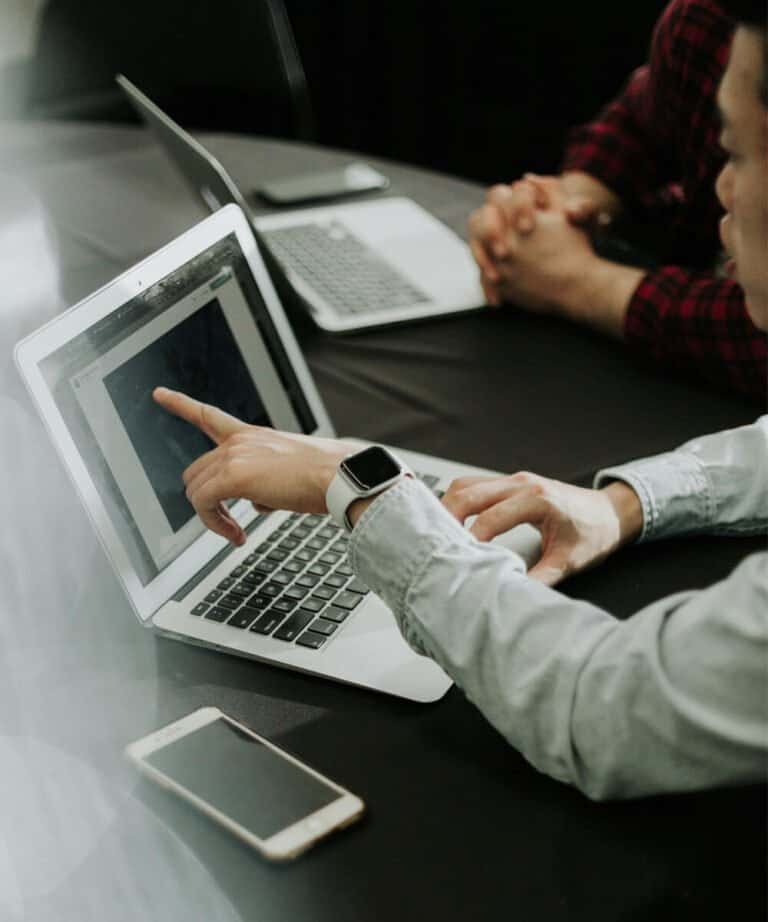 Business professionals discussing tax strategies on a laptop in a meeting room.